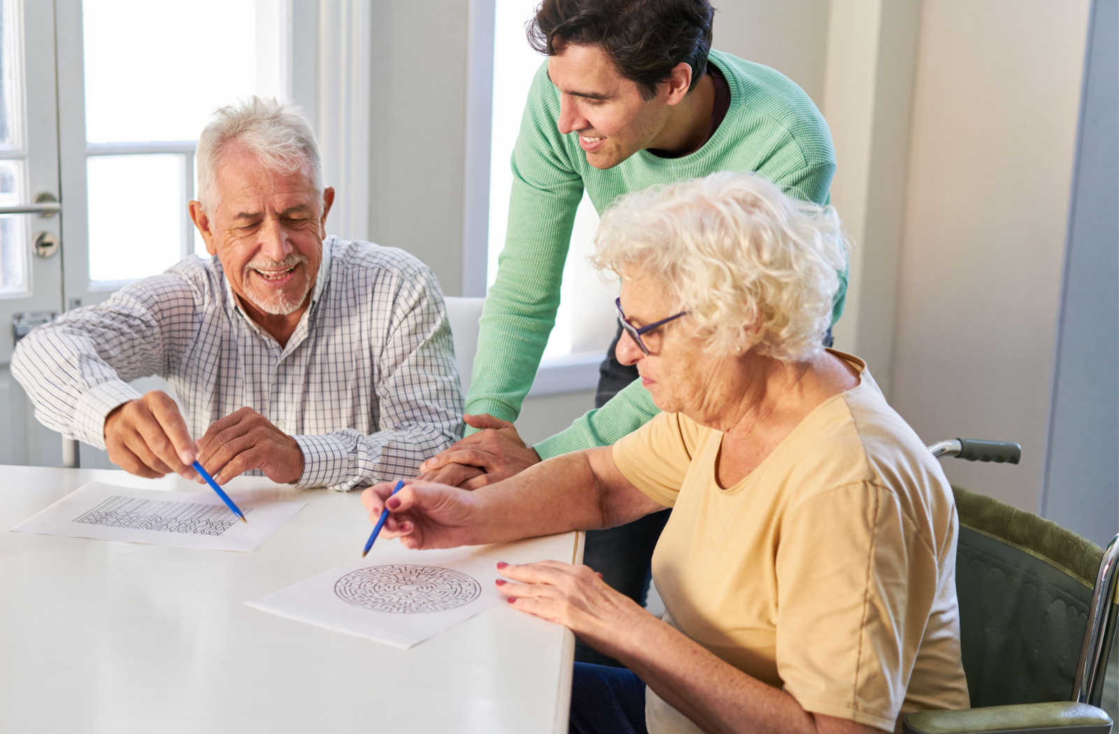 An aide helps two seniors do a memory activity.